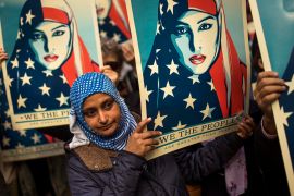Woman in hijab carries poster